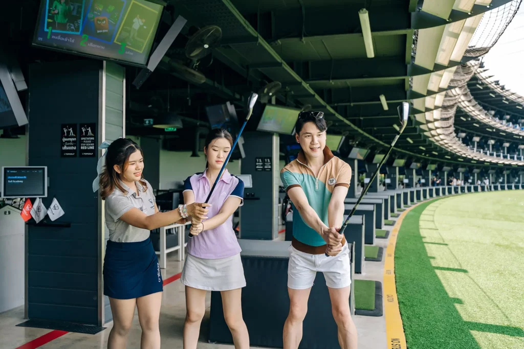A learning to play golf with an coach giving guidance on the driving range